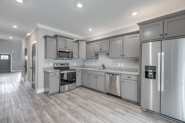 kitchen with gray cabinetry, sink, light hardwood / wood-style floors, and appliances with stainless steel finishes