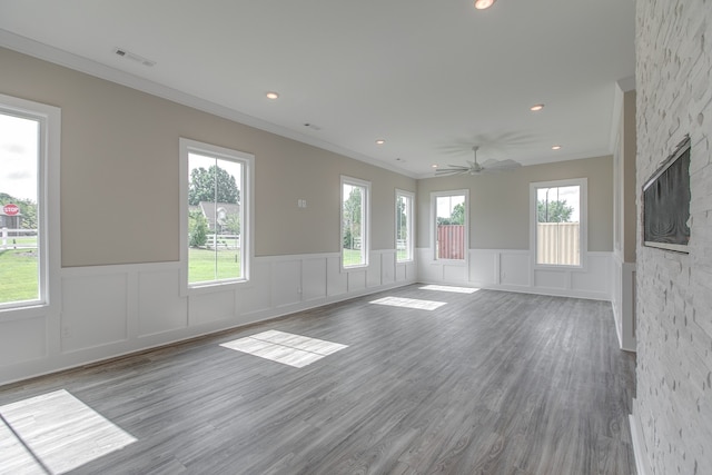 empty room with a wealth of natural light, hardwood / wood-style flooring, and ornamental molding