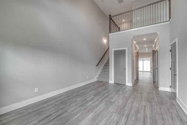 unfurnished living room with a high ceiling and light wood-type flooring