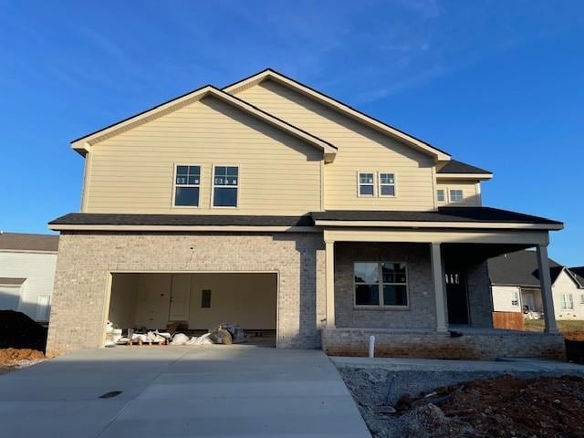 view of front of property with a garage, concrete driveway, a porch, and brick siding