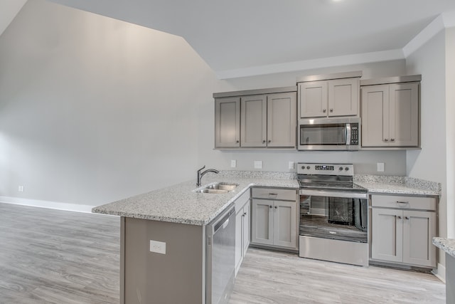 kitchen with light stone countertops, sink, kitchen peninsula, appliances with stainless steel finishes, and light wood-type flooring