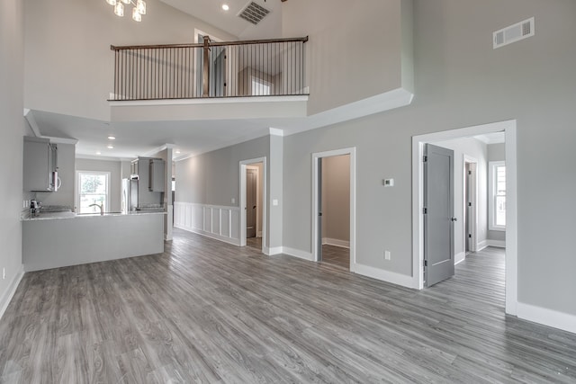 unfurnished living room featuring sink, high vaulted ceiling, and hardwood / wood-style flooring