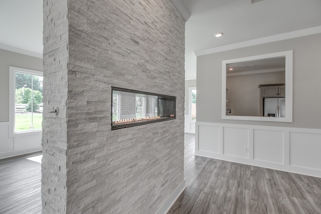 unfurnished living room with hardwood / wood-style flooring, ornamental molding, and a fireplace