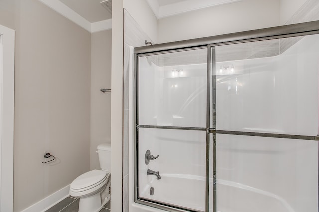 bathroom featuring combined bath / shower with glass door, tile patterned floors, and toilet