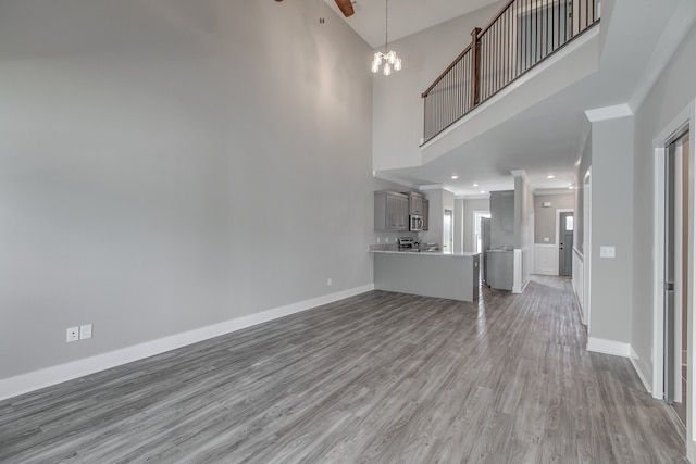 unfurnished living room with a high ceiling, an inviting chandelier, and wood-type flooring