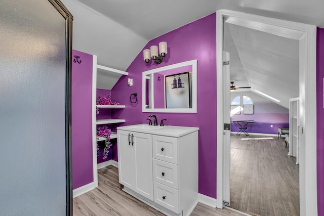 bathroom with ceiling fan, walk in shower, lofted ceiling, vanity, and hardwood / wood-style flooring