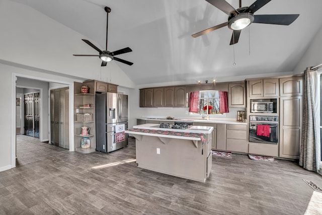 kitchen with a kitchen breakfast bar, a center island, appliances with stainless steel finishes, and vaulted ceiling