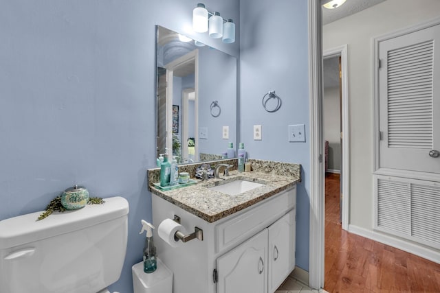 bathroom with wood-type flooring, vanity, and toilet