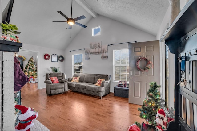 living room featuring hardwood / wood-style floors, high vaulted ceiling, ceiling fan, a textured ceiling, and beam ceiling