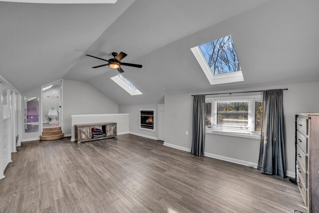 unfurnished living room with hardwood / wood-style floors, lofted ceiling with skylight, and ceiling fan