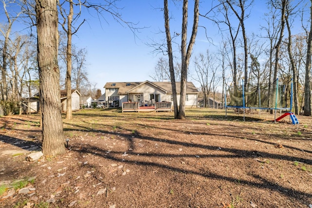 view of yard featuring a trampoline and a wooden deck
