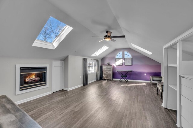additional living space featuring vaulted ceiling with skylight, ceiling fan, and dark hardwood / wood-style floors