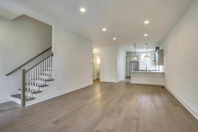 unfurnished living room with sink and light wood-type flooring