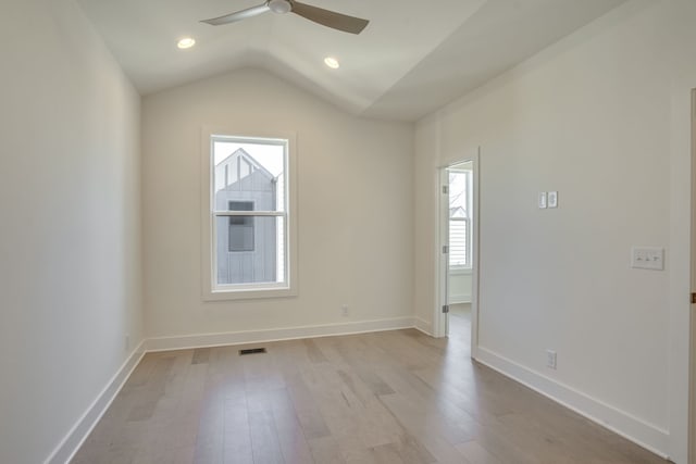 spare room featuring light wood-type flooring, vaulted ceiling, plenty of natural light, and ceiling fan