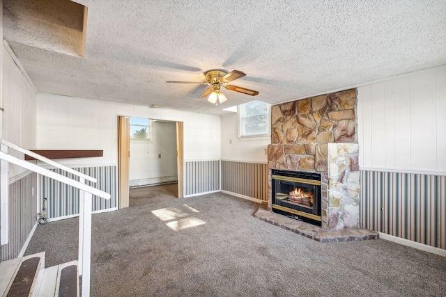 unfurnished living room featuring carpet, a textured ceiling, ceiling fan, a baseboard heating unit, and a fireplace