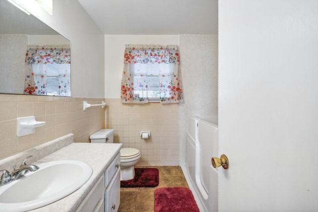 bathroom featuring tile patterned flooring, vanity, toilet, and tile walls