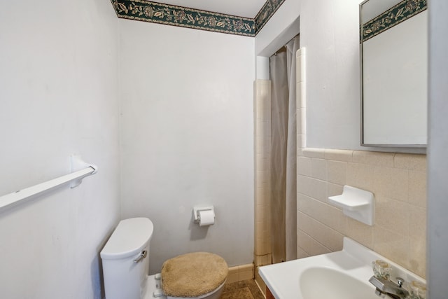 bathroom featuring sink, tile walls, and toilet