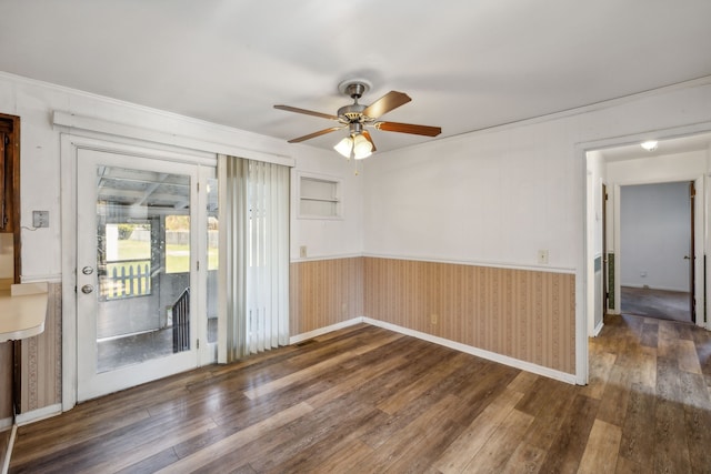 empty room featuring ceiling fan, dark wood-type flooring, and wood walls