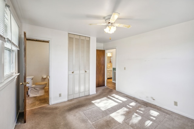 carpeted bedroom featuring ceiling fan, a closet, ensuite bathroom, and multiple windows