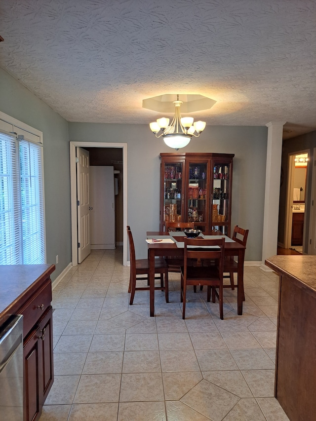 tiled dining room with a chandelier and a textured ceiling