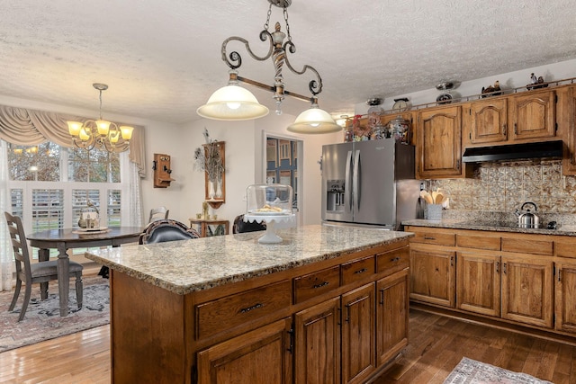 kitchen with an inviting chandelier, stainless steel fridge with ice dispenser, dark hardwood / wood-style flooring, pendant lighting, and a kitchen island