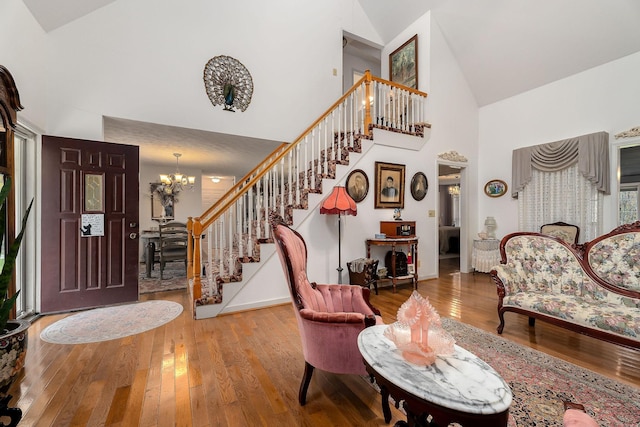 foyer entrance with hardwood / wood-style flooring, high vaulted ceiling, and an inviting chandelier