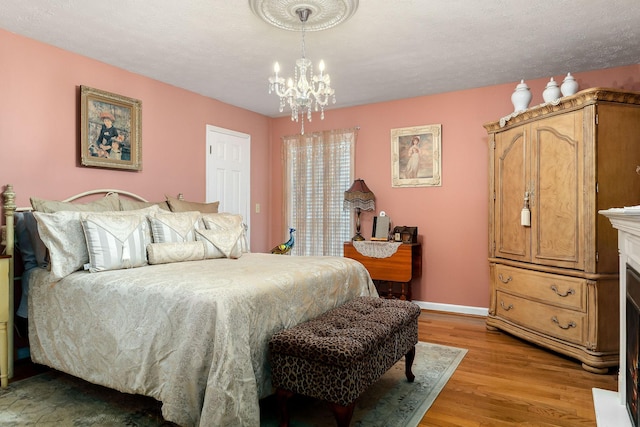 bedroom featuring a notable chandelier, light hardwood / wood-style floors, and a textured ceiling