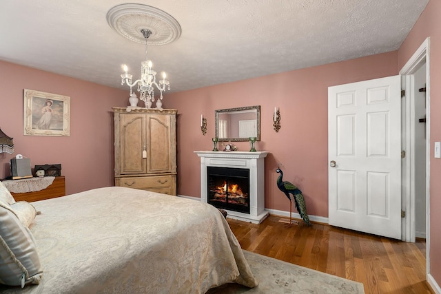 bedroom with a textured ceiling, hardwood / wood-style flooring, and a notable chandelier