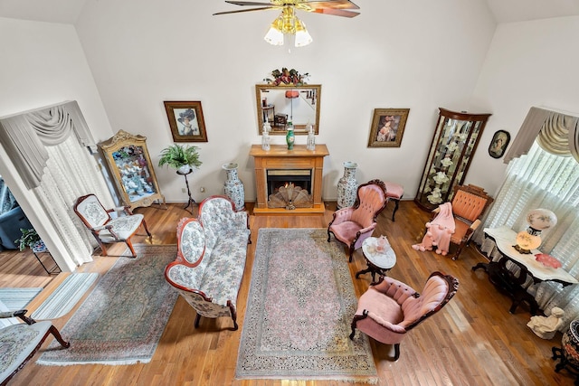 living room with hardwood / wood-style flooring, ceiling fan, and high vaulted ceiling