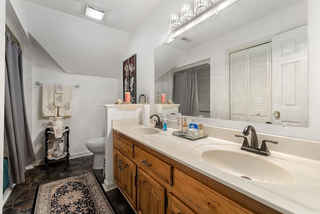 bathroom featuring vanity, vaulted ceiling, and toilet