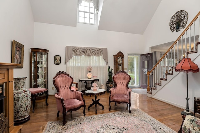 sitting room with hardwood / wood-style floors, plenty of natural light, and high vaulted ceiling