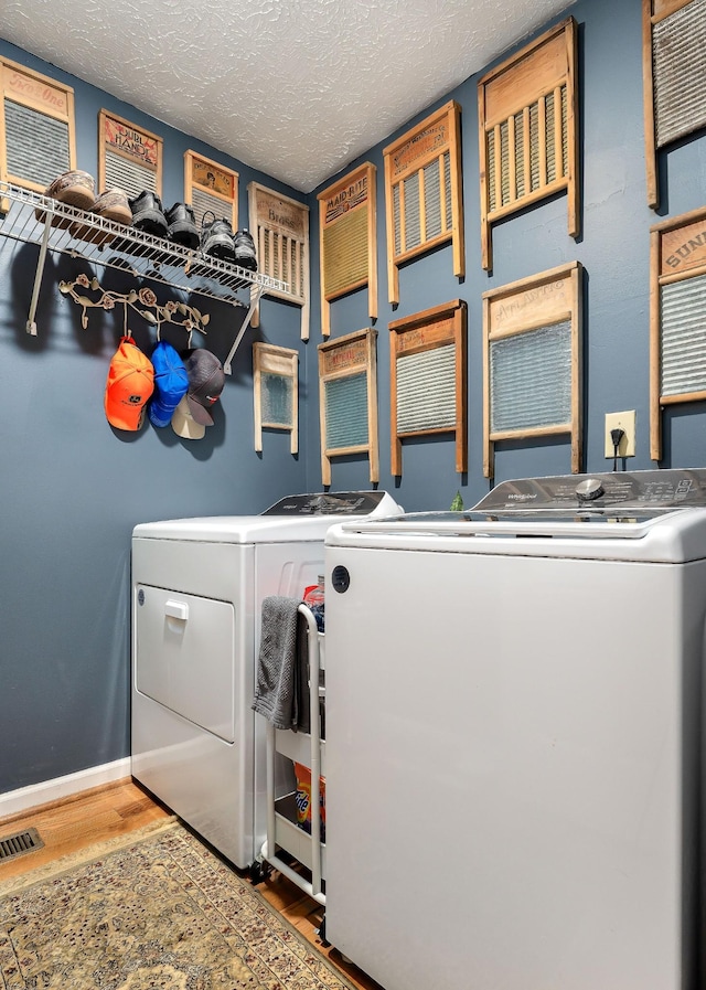 washroom featuring wood-type flooring, a textured ceiling, and washing machine and clothes dryer