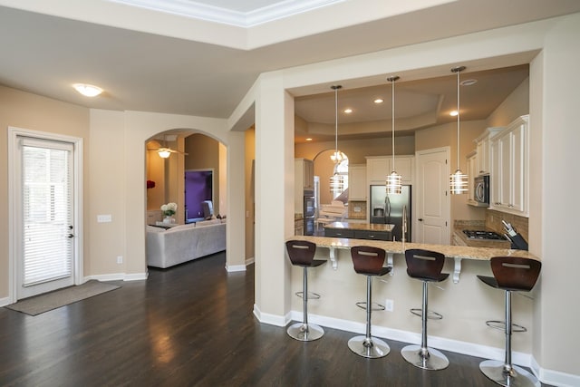 kitchen with decorative light fixtures, kitchen peninsula, stainless steel appliances, and a breakfast bar