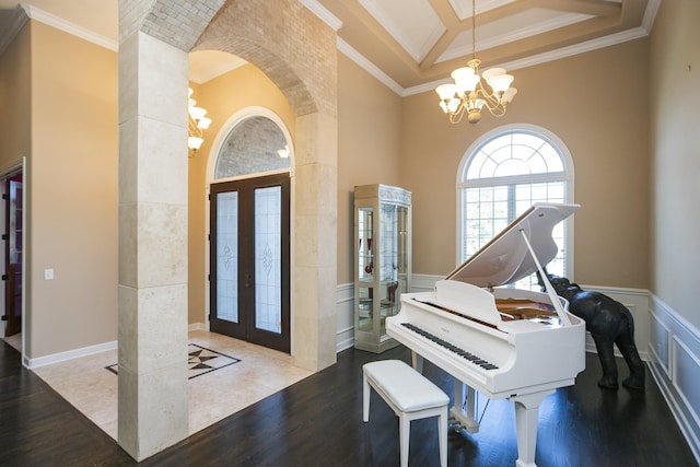 entryway with an inviting chandelier, wood-type flooring, crown molding, and french doors