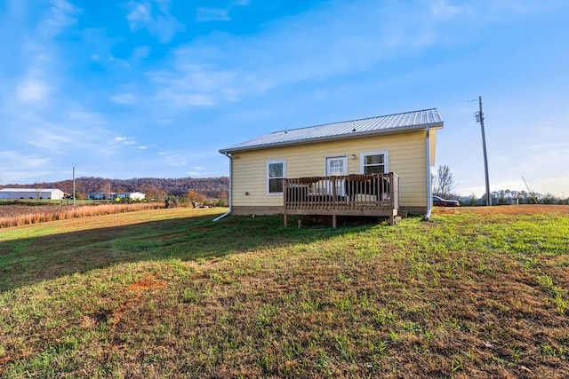 back of property with a wooden deck and a yard