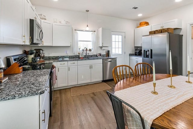 kitchen featuring dark stone counters, white cabinets, sink, light hardwood / wood-style floors, and stainless steel appliances