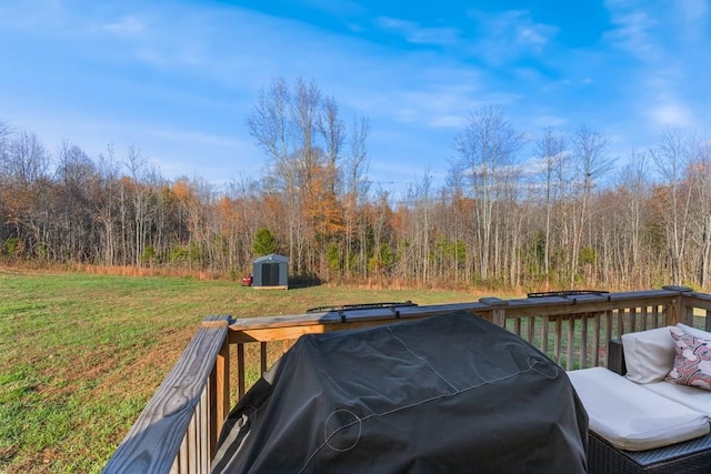 wooden deck featuring a storage unit, a grill, and a yard