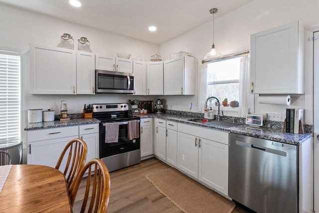 kitchen featuring sink, hanging light fixtures, light hardwood / wood-style flooring, white cabinetry, and stainless steel appliances