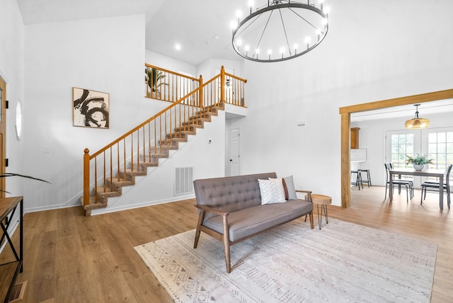 living room with a towering ceiling, light wood-type flooring, and a notable chandelier