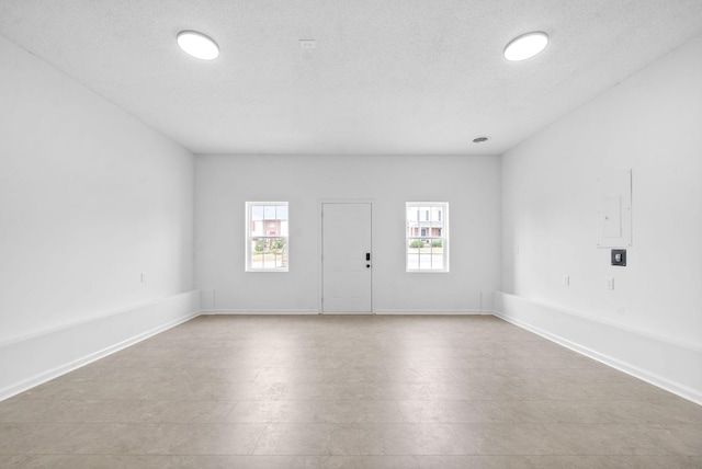 empty room featuring electric panel, light tile patterned flooring, and a textured ceiling