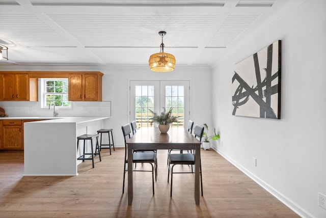 dining space featuring french doors, light wood-type flooring, crown molding, and coffered ceiling