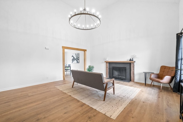 sitting room with light hardwood / wood-style flooring, high vaulted ceiling, and an inviting chandelier