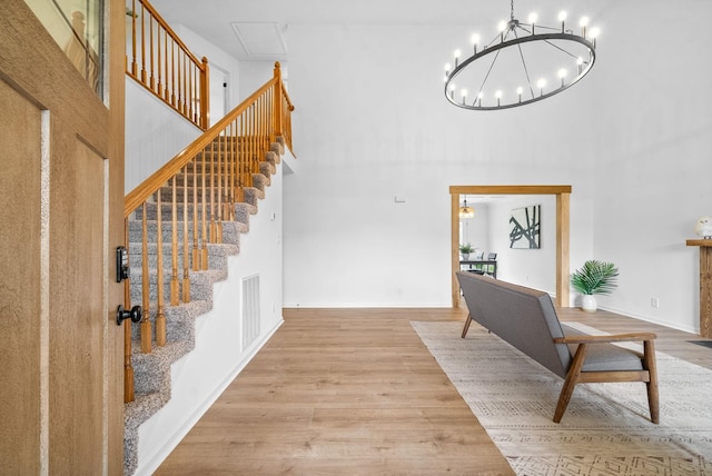 foyer entrance featuring a chandelier, a towering ceiling, and light hardwood / wood-style flooring