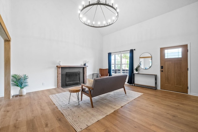 living room featuring high vaulted ceiling, a chandelier, a tile fireplace, and light hardwood / wood-style flooring