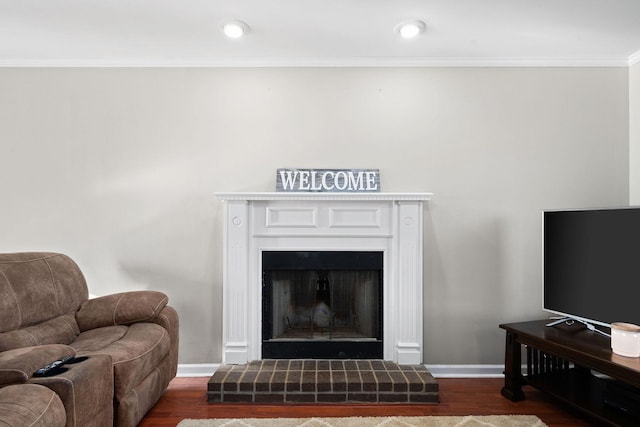 living room with ornamental molding, dark wood-type flooring, and a brick fireplace