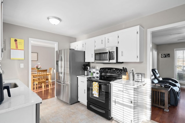 kitchen featuring light stone countertops, stainless steel appliances, white cabinetry, and light hardwood / wood-style floors