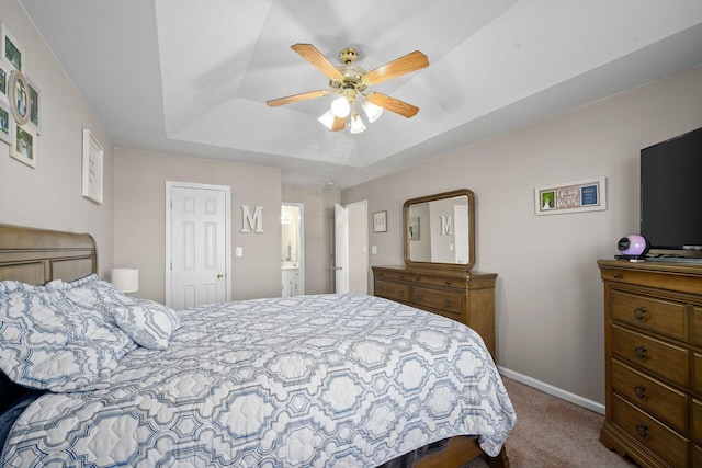 carpeted bedroom with a raised ceiling, ceiling fan, a closet, and ensuite bathroom