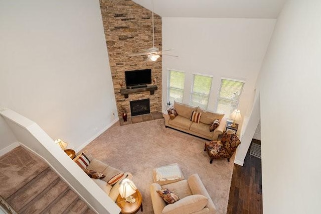 living room with a stone fireplace, ceiling fan, high vaulted ceiling, and dark hardwood / wood-style floors