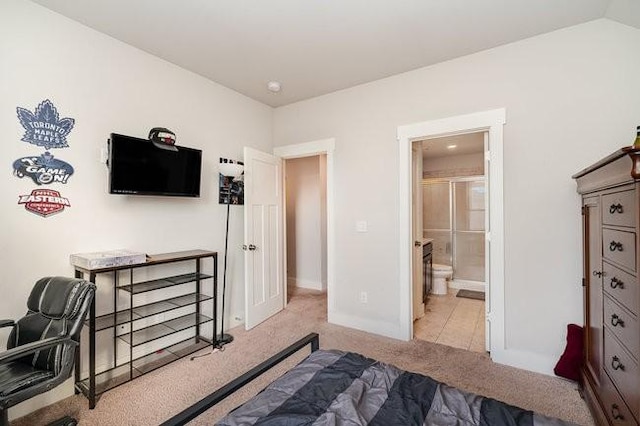 bedroom featuring light colored carpet, lofted ceiling, and ensuite bath