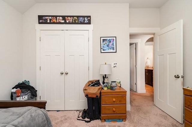 bedroom featuring vaulted ceiling, light colored carpet, and a closet